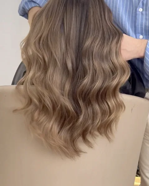 Balayage blond clair ondulé vu de dos, en fin de brushing