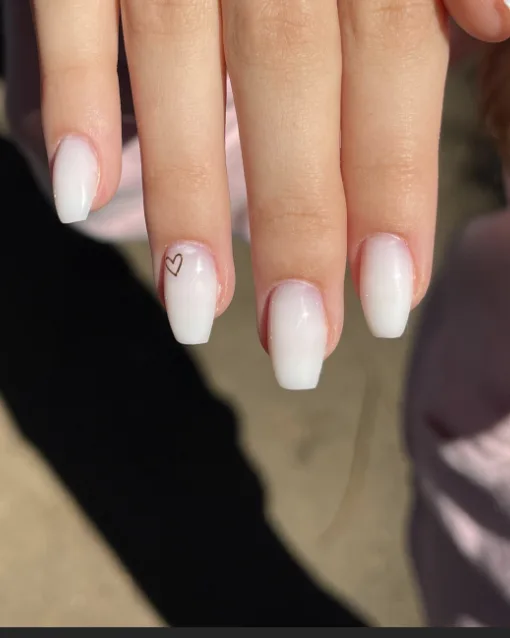 Ongles baby boomer blancs, avec un petit cœur tracé sur un ongle