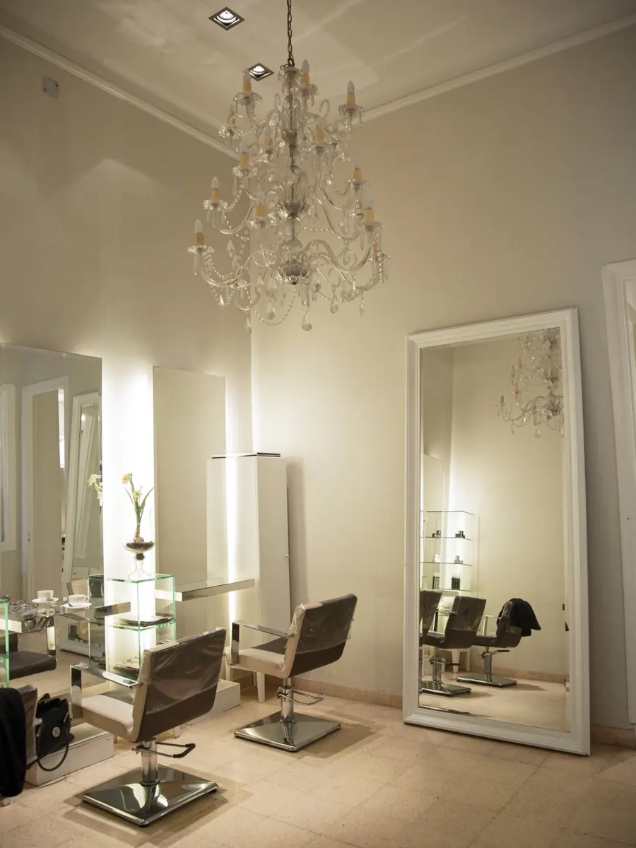 Salle du salon, haut plafond, lustre en verre et grand miroir posé contre le mur ivoire